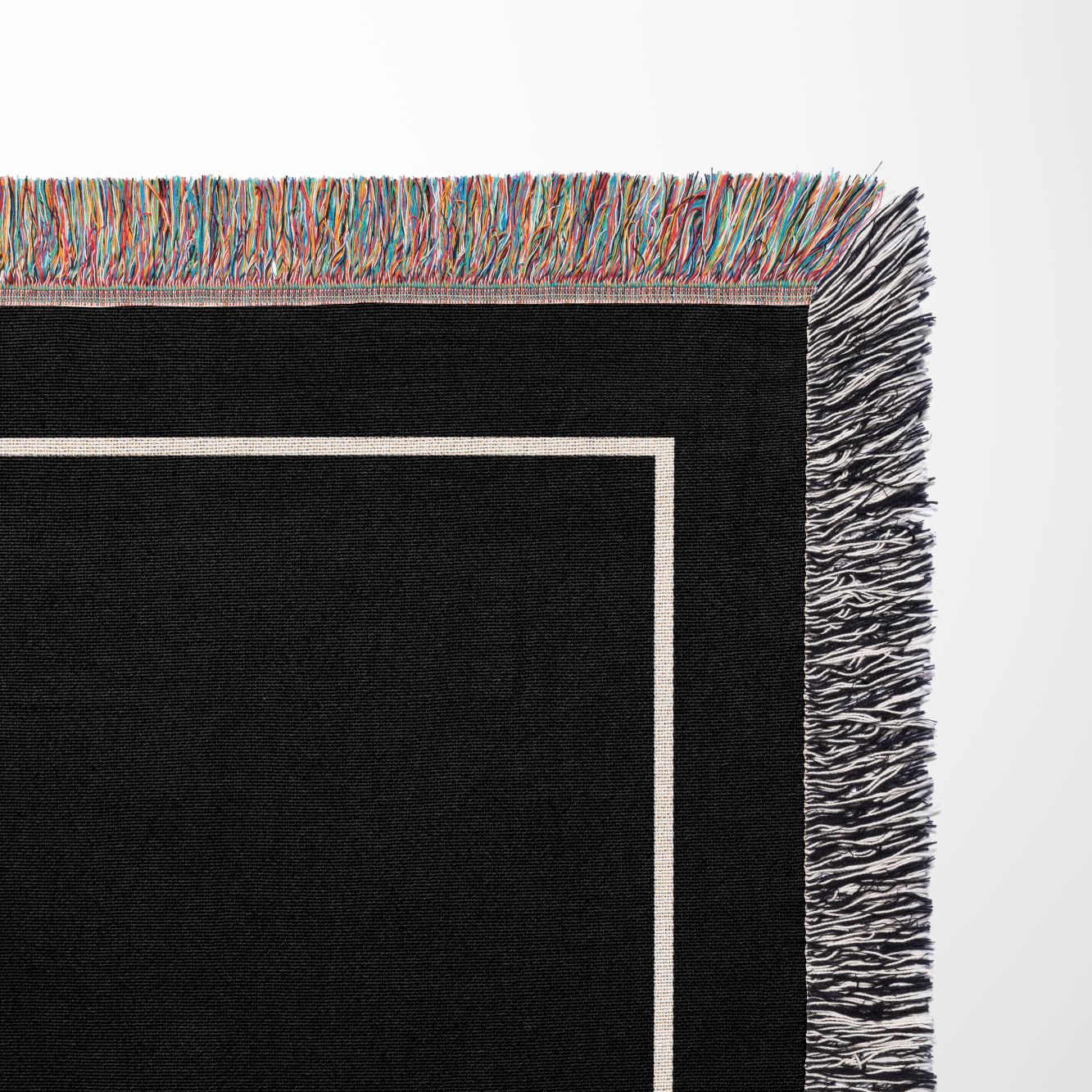 Corner of custom black throw blanket with colorful fringe on a white background from The Blanket Shop
