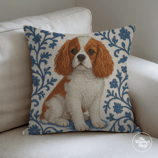 Custom throw pillow with a cute long eared dog and blue and white floral design on a white couch with The Blanket Shop Logo