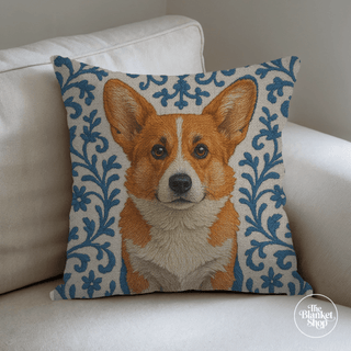 Decorative pillow with a cute corgi dog and blue floral background on a white couch, with The Blanket Shop Logo