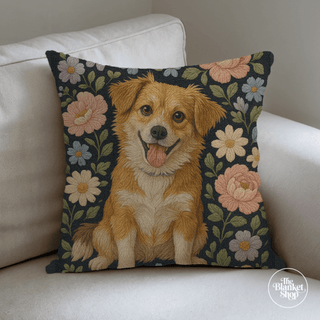 Decorative pillow with a dog illustration on a floral background, placed on a white couch and The Blanket Shop Logo