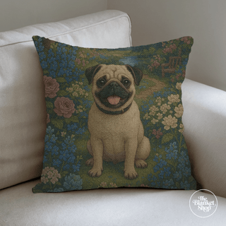 Decorative pillow with a pug design on a floral background, placed on a white couch with The Blanket Shop Logo