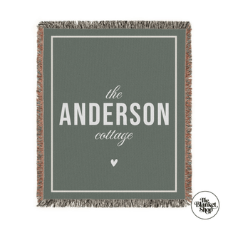 Green blanket with 'the Anderson cottage' text and a heart symbol, featuring The Blanket Shop Logo