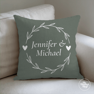 Green pillow with 'Jennifer & Michael' text on a beige couch and The Blanket Shop Logo