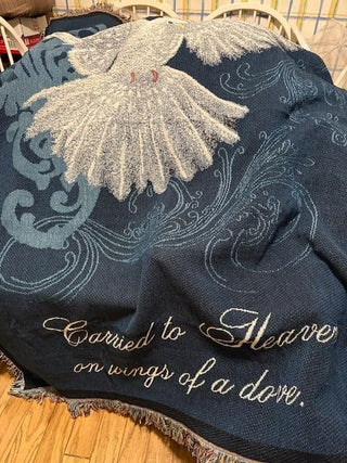 Navy blue blanket with white embroidery and text on a wooden floor.