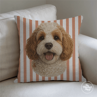 Pillow with a dog design on a striped background with The Blanket Shop Logo