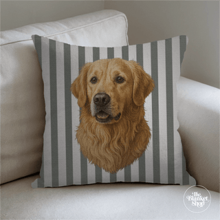 Pillow with a dog's face design on a striped background, placed on a couch with The Blanket Shop Logo