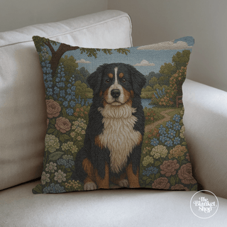 Woven blanket with a bernese mountain dog, flower garden, and pond design, featuring 'The Blanket Shop' logo.