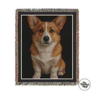 Woven blanket with a corgi design on a black background, featuring 'The Blanket Shop' logo.