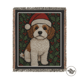 Woven blanket with a dog wearing a Santa hat and holly design, featuring 'The Blanket Shop' logo.