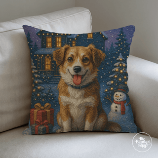 Woven pillow with a dog and Christmas scene design, featuring a house, trees, and snowman and The Blanket Shop Logo